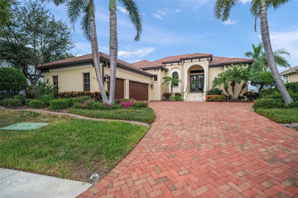 A single-story house with a brick paver driveway, a tiled roof, and palm trees — 4110 COMMODORE BOULEVARD, CORTEZ, FL