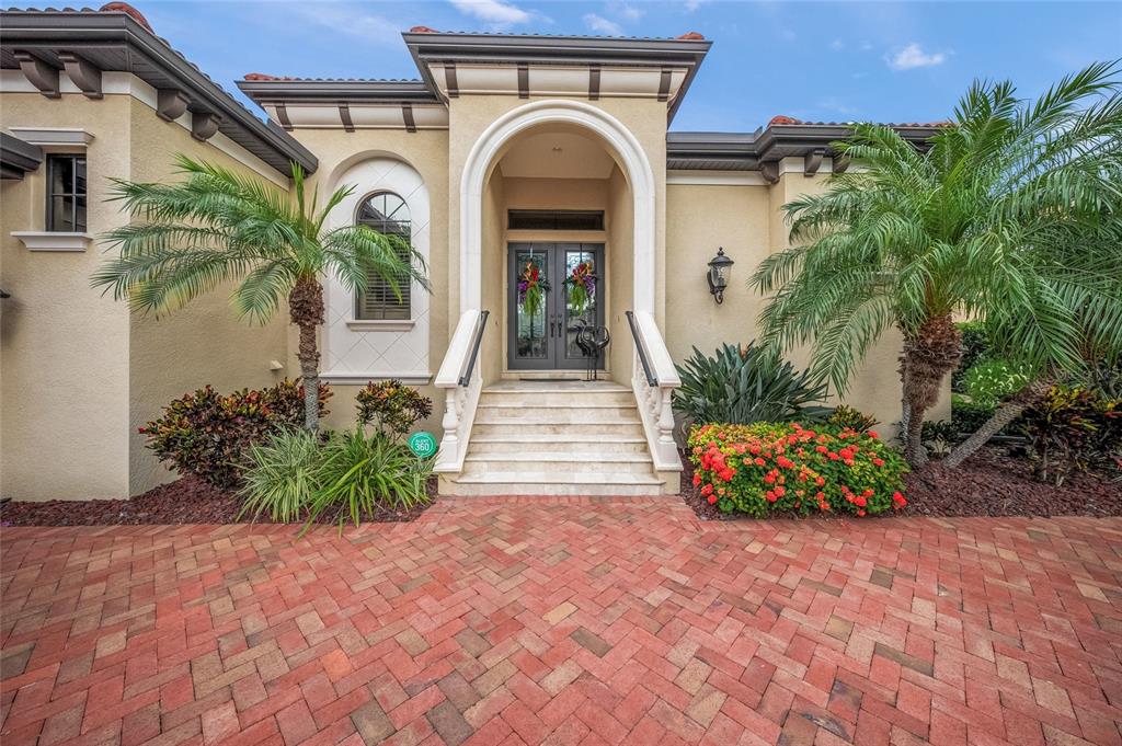 The exterior of a stucco home features a brick paver driveway and arched entryway — 4110 COMMODORE BOULEVARD, CORTEZ, FL