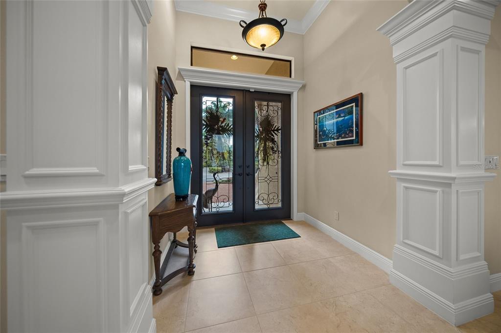 An entryway features a double front door with decorative glass, tile flooring, and white columns — 4110 COMMODORE BOULEVARD, CORTEZ, FL