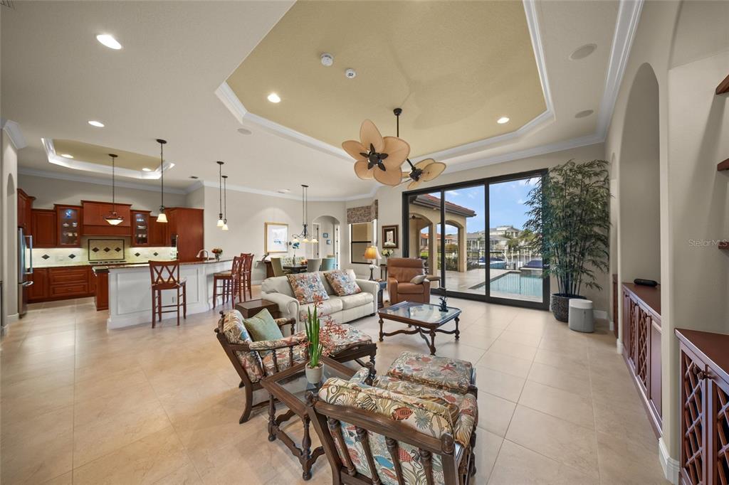 An open-concept living room and kitchen with tile floors, a tray ceiling, and sliding glass doors — 4110 COMMODORE BOULEVARD, CORTEZ, FL
