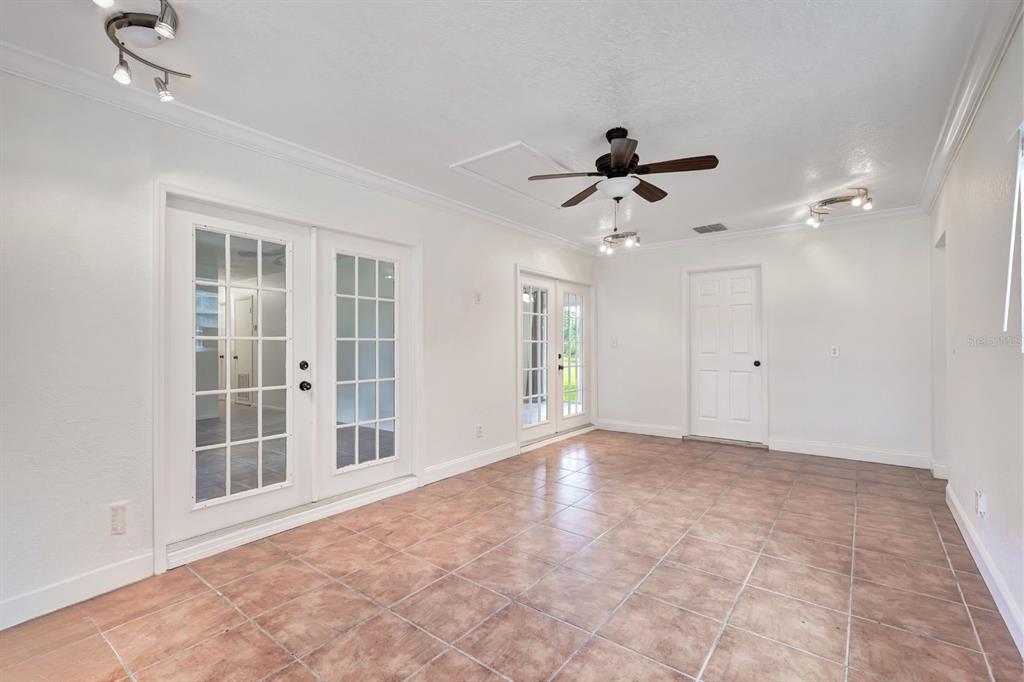 A bright room features white walls, tile flooring, a ceiling fan, and multiple glass-paned doors — 2445 OLD HICKORY TREE ROAD, ST CLOUD, FL