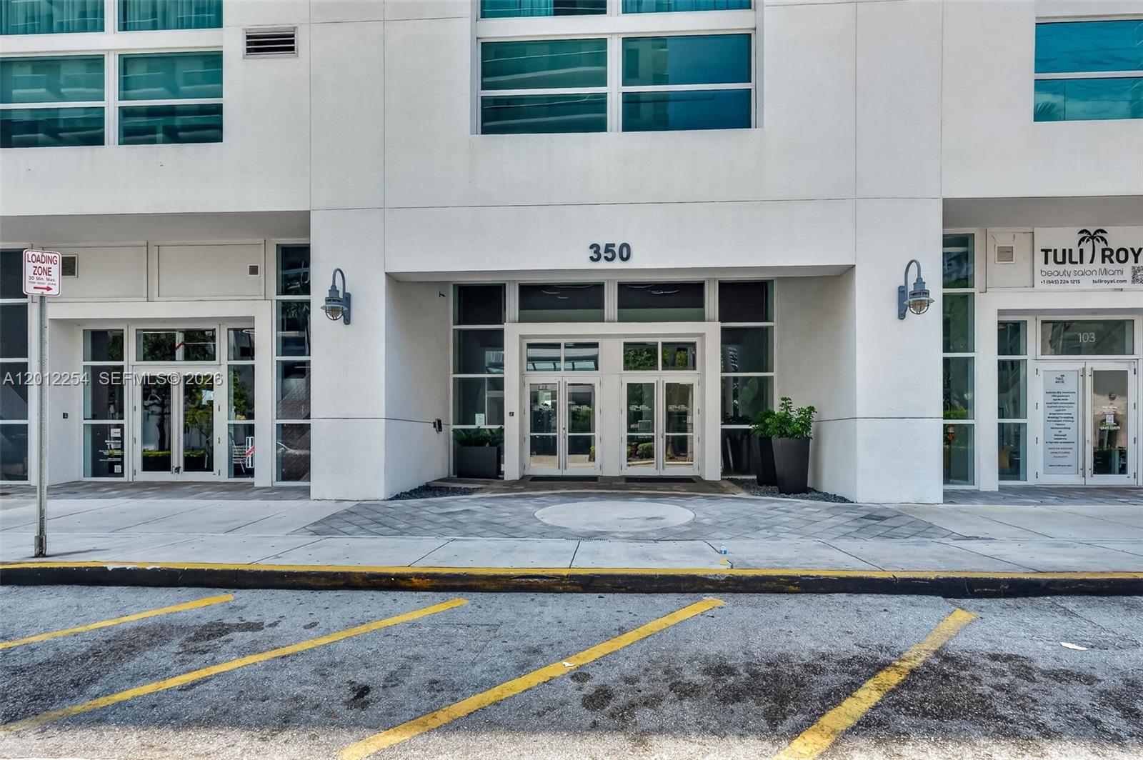 The exterior of a building entrance features glass double doors, a loading zone sign, and signage — 350 NE 24th St # 609, Miami FL 33137, MIAMI, FL