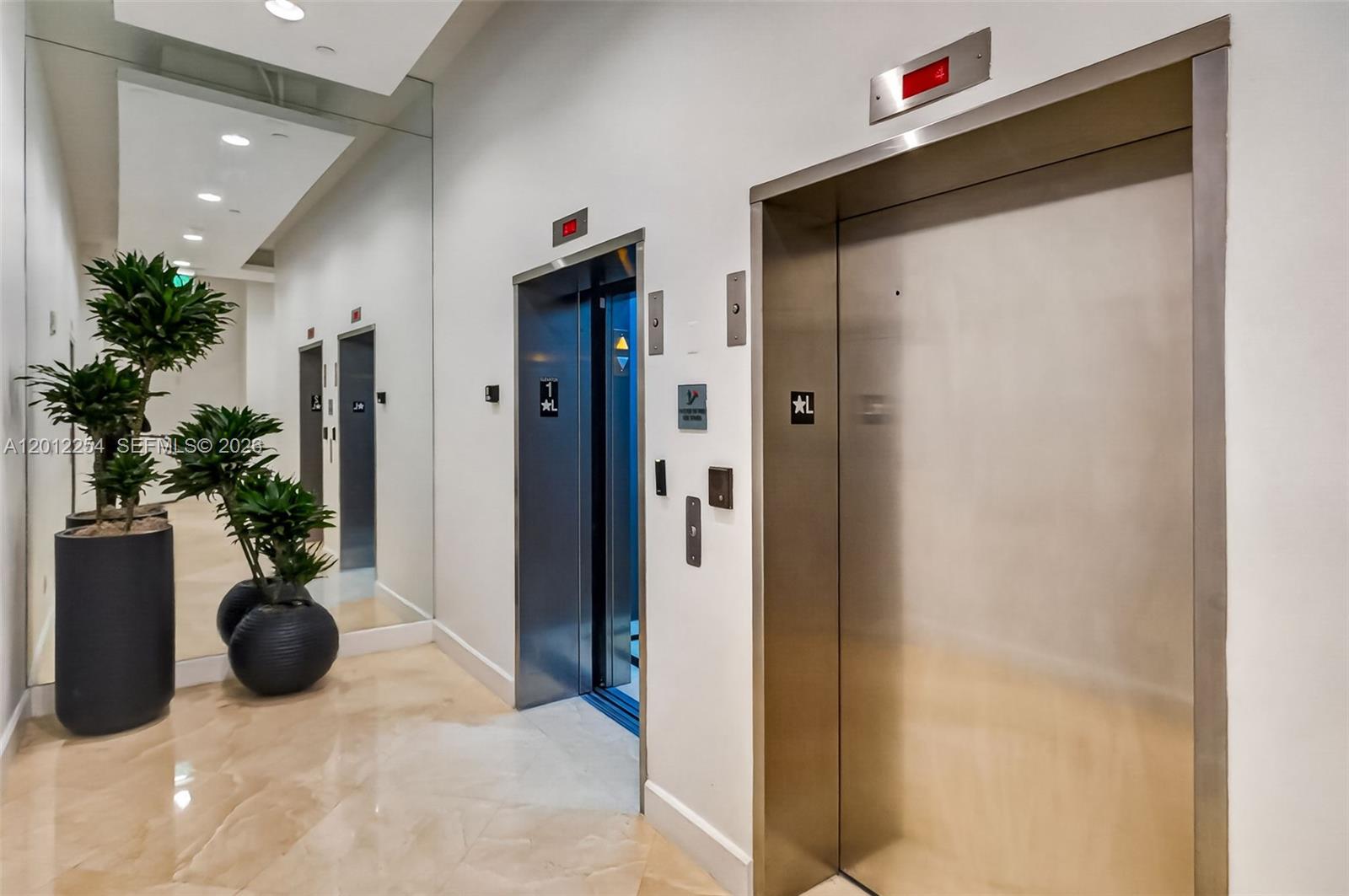 Two stainless steel elevators are situated in a hallway with a large floor mirror — 350 NE 24th St # 609, Miami FL 33137, MIAMI, FL