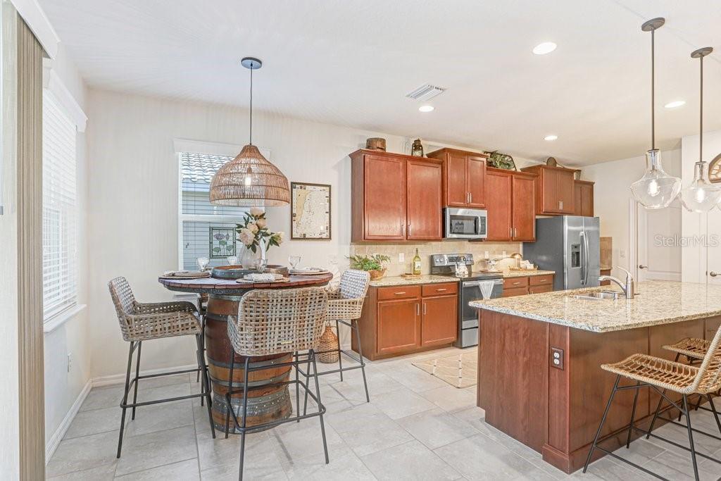 A kitchen features wood cabinets, granite countertops, a center island with bar stools, and stainless appliances — 2807 ORIOLE DRIVE, SARASOTA, FL