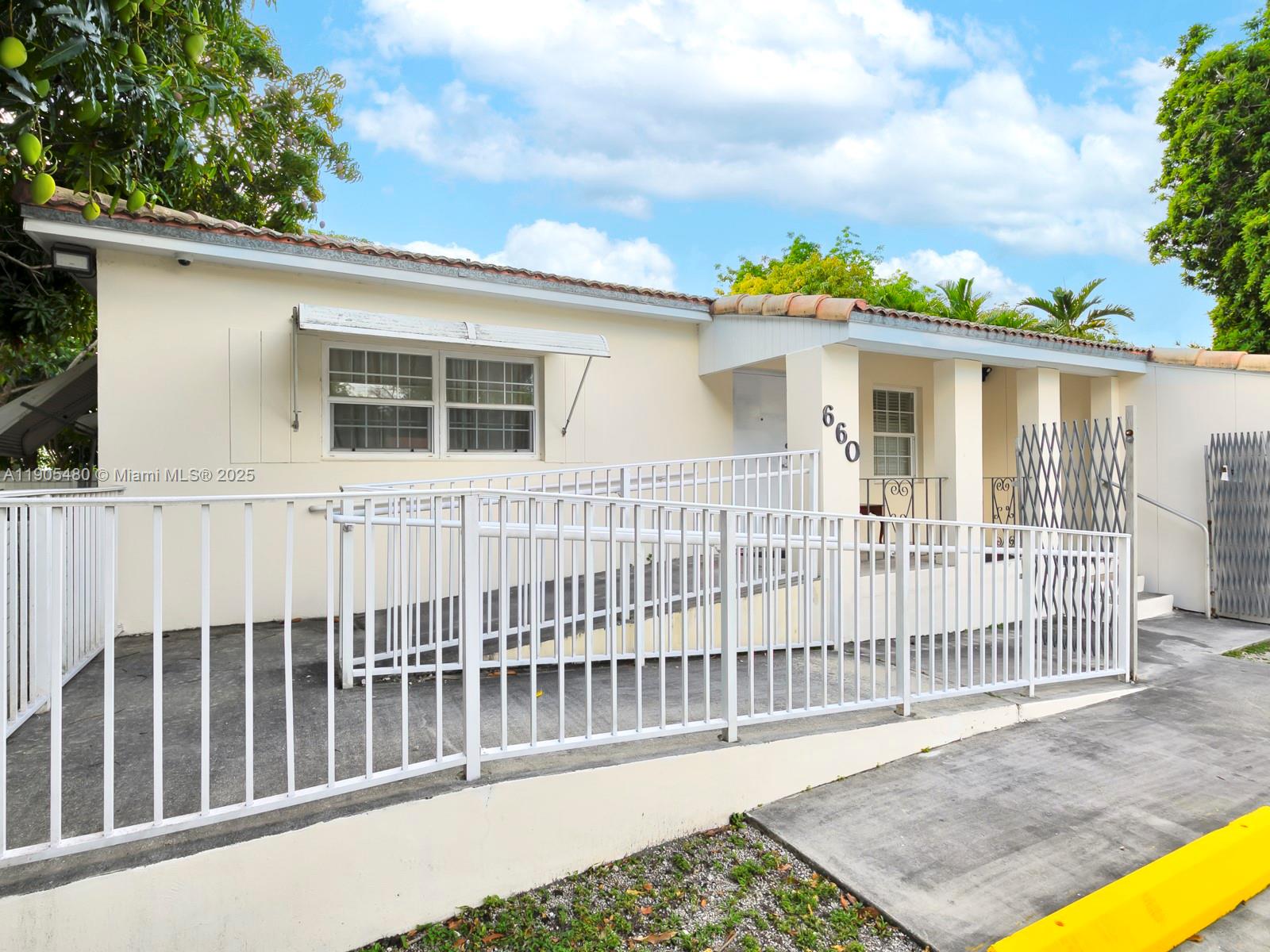 A single-story house features a white metal wheelchair ramp leading to a covered front entrance — 660 Miller Dr, Miami Springs FL 33166, MIAMI SPRINGS, FL