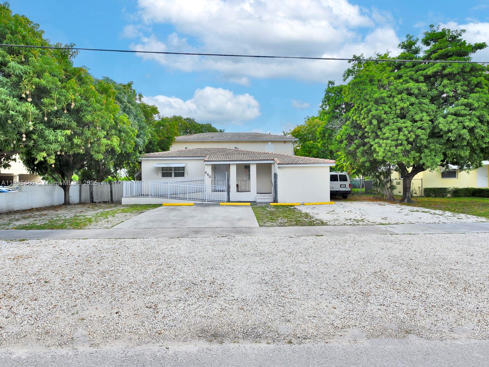 A one-story house with a wheelchair ramp, a gravel driveway, and large shade trees — 660 Miller Dr, Miami Springs FL 33166, MIAMI SPRINGS, FL