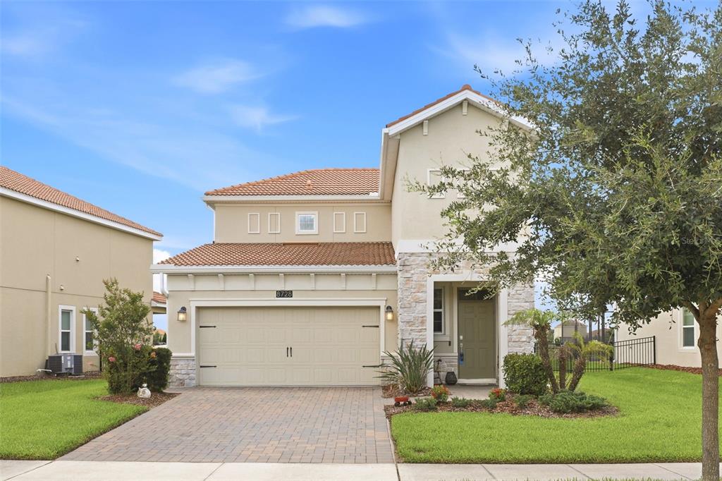 A kitchen features dark wood cabinets, white countertops, a central island with barstools, and tile flooring — 8728 PACIFIC DUNES DRIVE, DAVENPORT, FL
