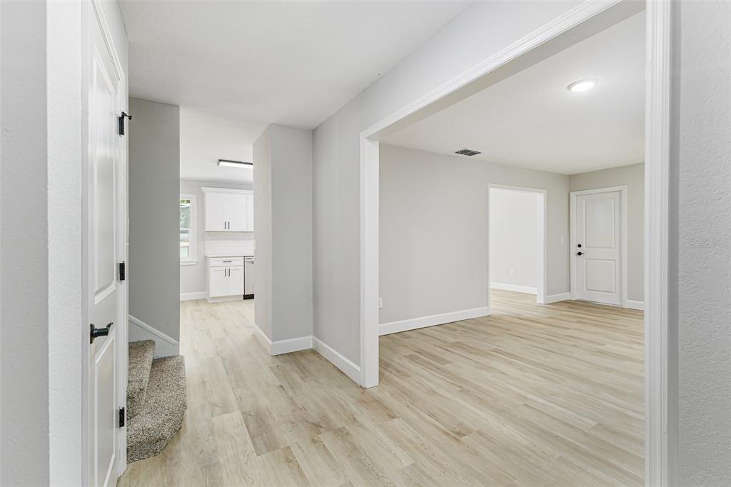 An interior view shows a hallway with light wood flooring, carpeted stairs, and white walls — 7520 HAVENWOOD DRIVE, LAKELAND, FL