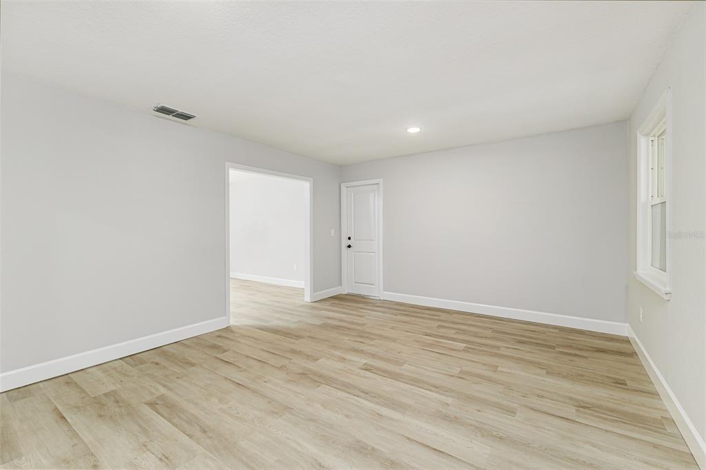 An empty room with light gray walls, wood-look flooring, and a white interior door — 7520 HAVENWOOD DRIVE, LAKELAND, FL