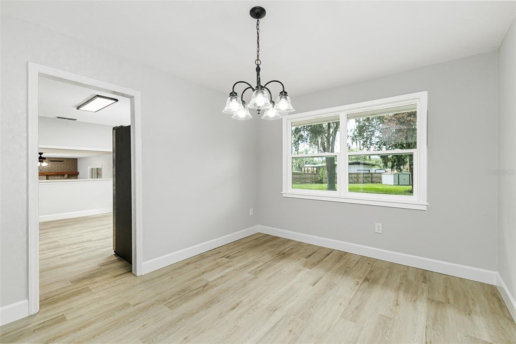 A dining room with light gray walls, wood-look flooring, a chandelier, and a large window — 7520 HAVENWOOD DRIVE, LAKELAND, FL