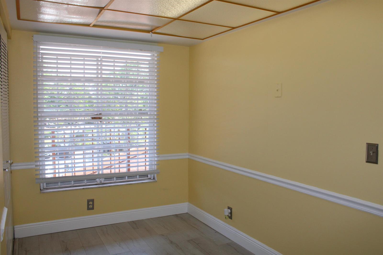 An empty room with yellow walls, white chair rail molding, and a window with blinds — 14671 Bonaire Boulevard # 305, Delray Beach FL 33446, DELRAY BEACH, FL