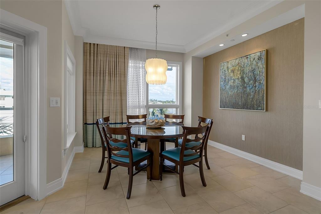 A dining room features a round wooden table, six chairs, a pendant light, and artwork — 915 SEASIDE DRIVE UNIT 410, Weeks 4-7, SARASOTA, FL
