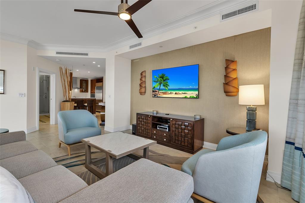 A living room features a wall-mounted television, two light blue armchairs, and a sectional sofa — 915 SEASIDE DRIVE UNIT 410, Weeks 4-7, SARASOTA, FL