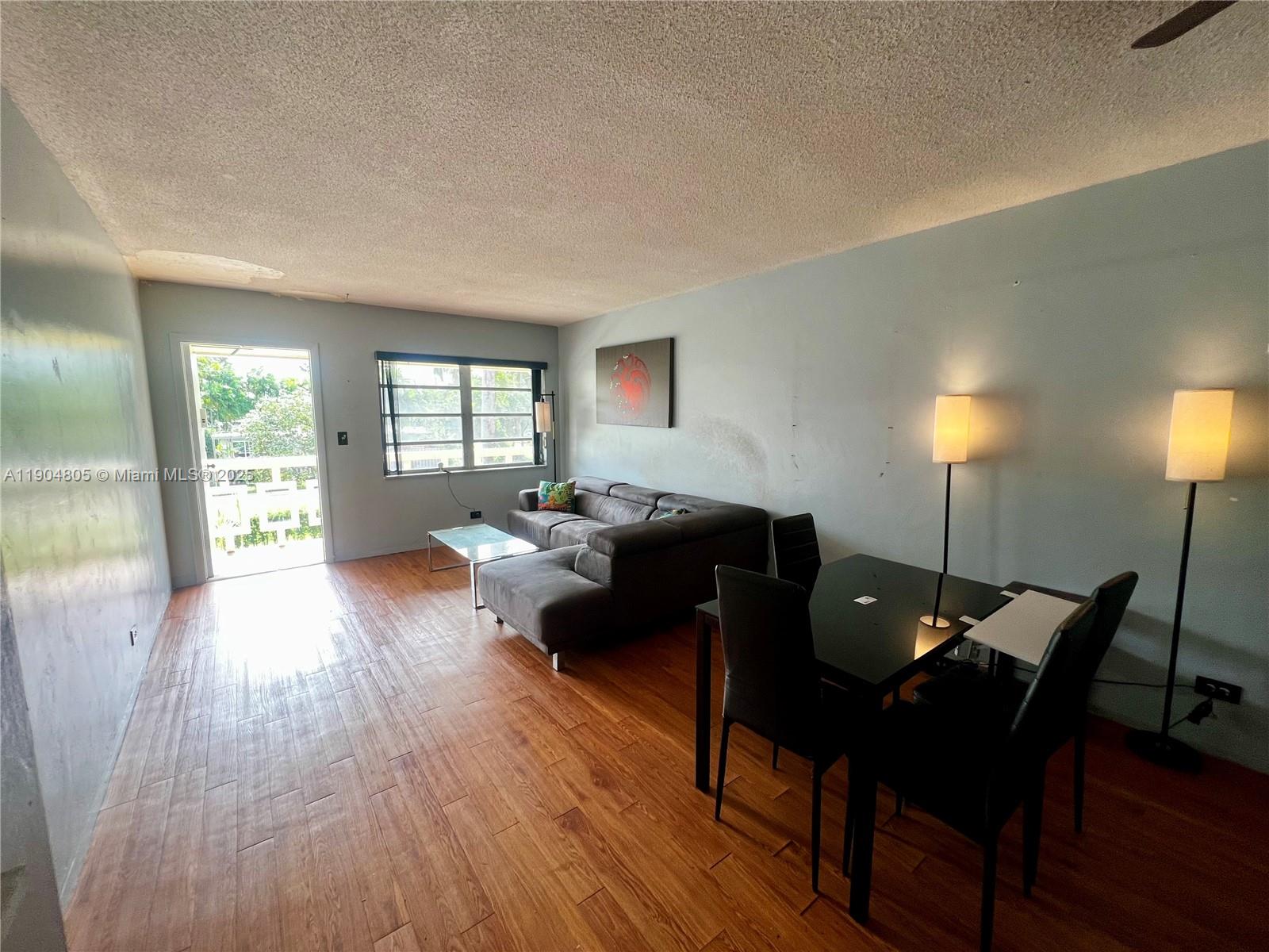 A living and dining area features wood-look flooring, a gray sectional sofa, and two lamps — 1501 Arthur St # 7, Hollywood FL 33020, HOLLYWOOD, FL