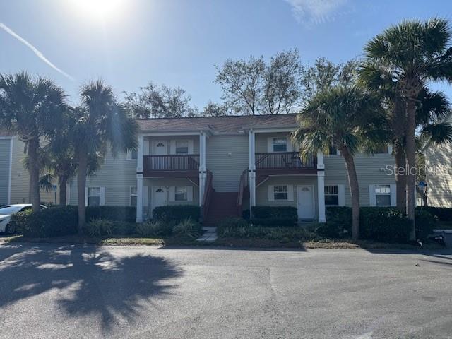A two-story apartment building with light siding, wooden balconies, and palm trees in front — 6740 MOONGLOW DRIVE UNIT 201, PORT RICHEY, FL