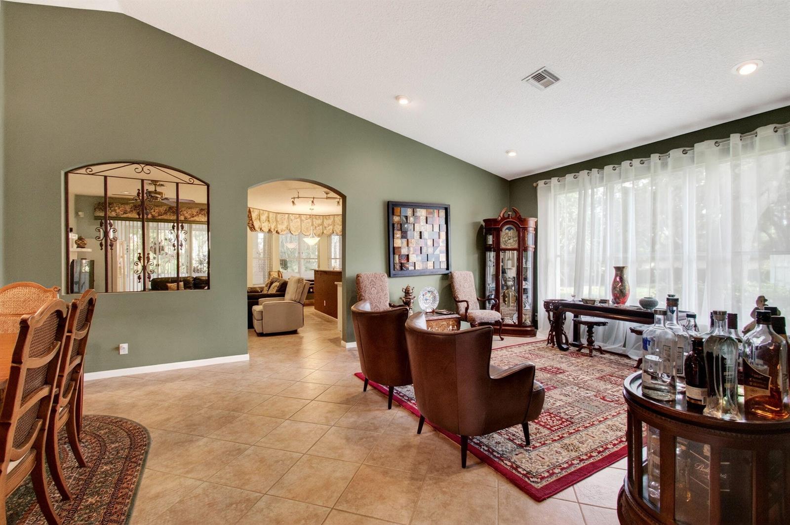 A living room with green walls, tile floors, an arched doorway, and a grandfather clock — 6453 Emerald Breeze Way, Boynton Beach FL 33437, BOYNTON BEACH, FL