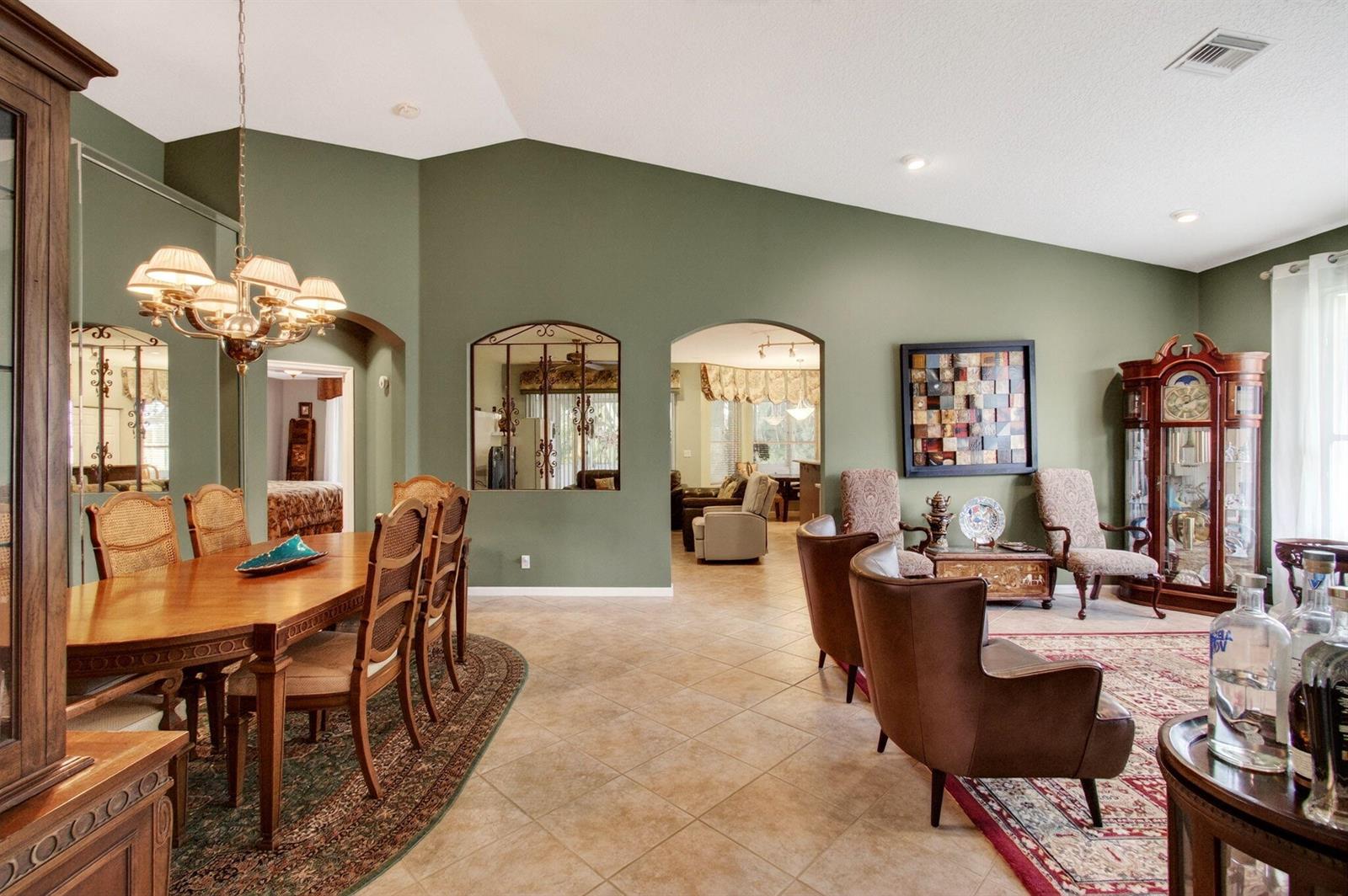 A dining area and living room with sage green walls, tile floors, and arched openings — 6453 Emerald Breeze Way, Boynton Beach FL 33437, BOYNTON BEACH, FL
