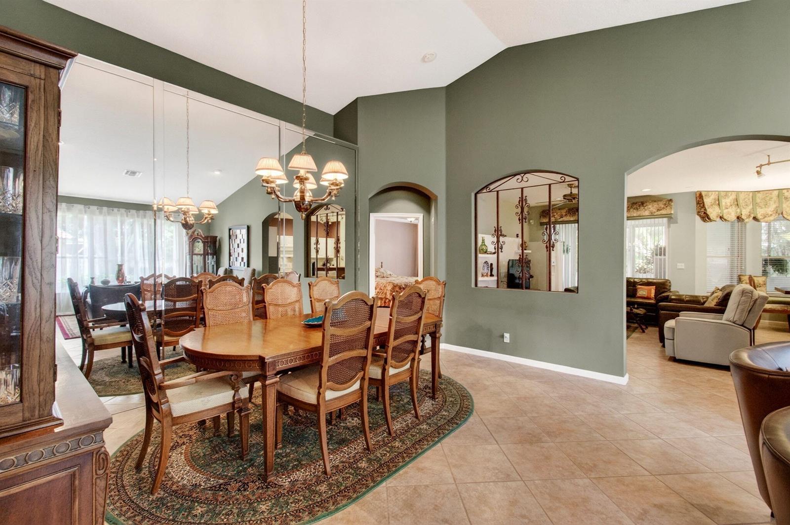 A dining room with a wooden table, cane-back chairs, mirrored walls, and sage green paint — 6453 Emerald Breeze Way, Boynton Beach FL 33437, BOYNTON BEACH, FL