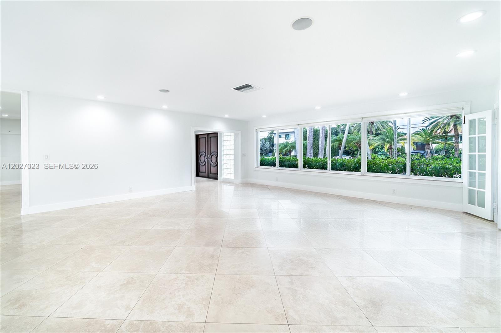 A spacious, empty room features large windows, light-colored tile flooring, and recessed ceiling lighting — 9835 W Broadview Dr, Bay Harbor Islands FL 33154, BAY HARBOR ISLANDS, FL