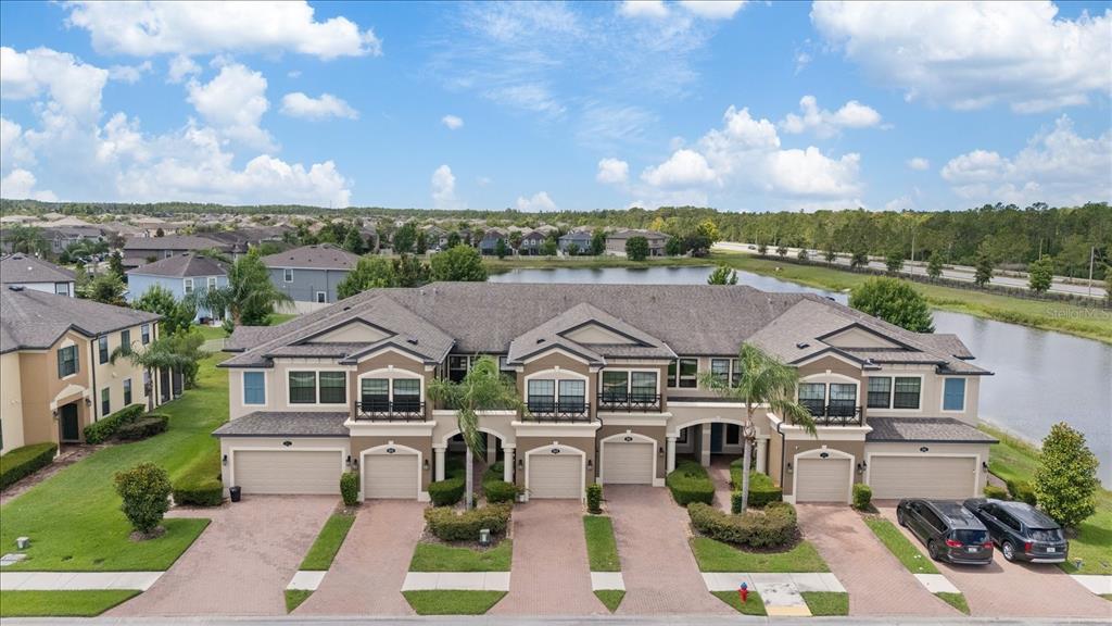 An aerial view of a multi-unit townhouse complex with attached garages and a lake behind — 18876 BEAUTYBERRY COURT, LUTZ, FL