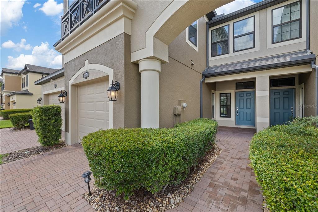 A view of a two-story townhouse exterior with a brick walkway and manicured hedges — 18876 BEAUTYBERRY COURT, LUTZ, FL