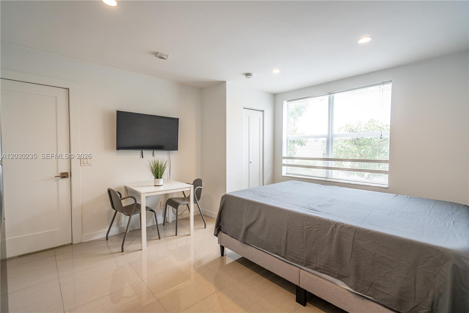 A bedroom features a bed, a small dining table with two chairs, and a television — 924 Marseille Dr # 26, Miami Beach FL 33141, MIAMI BEACH, FL