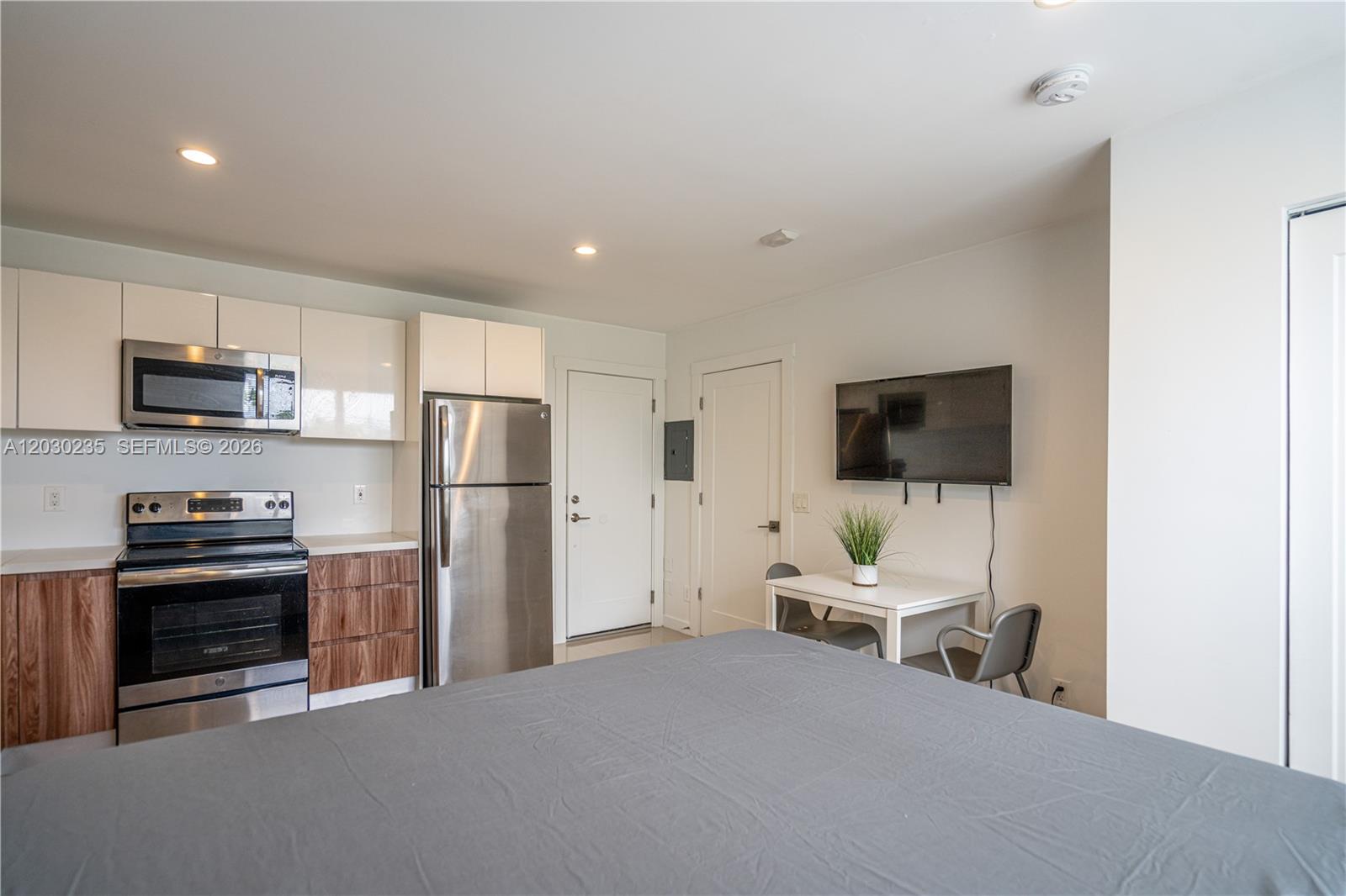 A studio apartment features a kitchen with stainless steel appliances and a dining area — 924 Marseille Dr # 26, Miami Beach FL 33141, MIAMI BEACH, FL