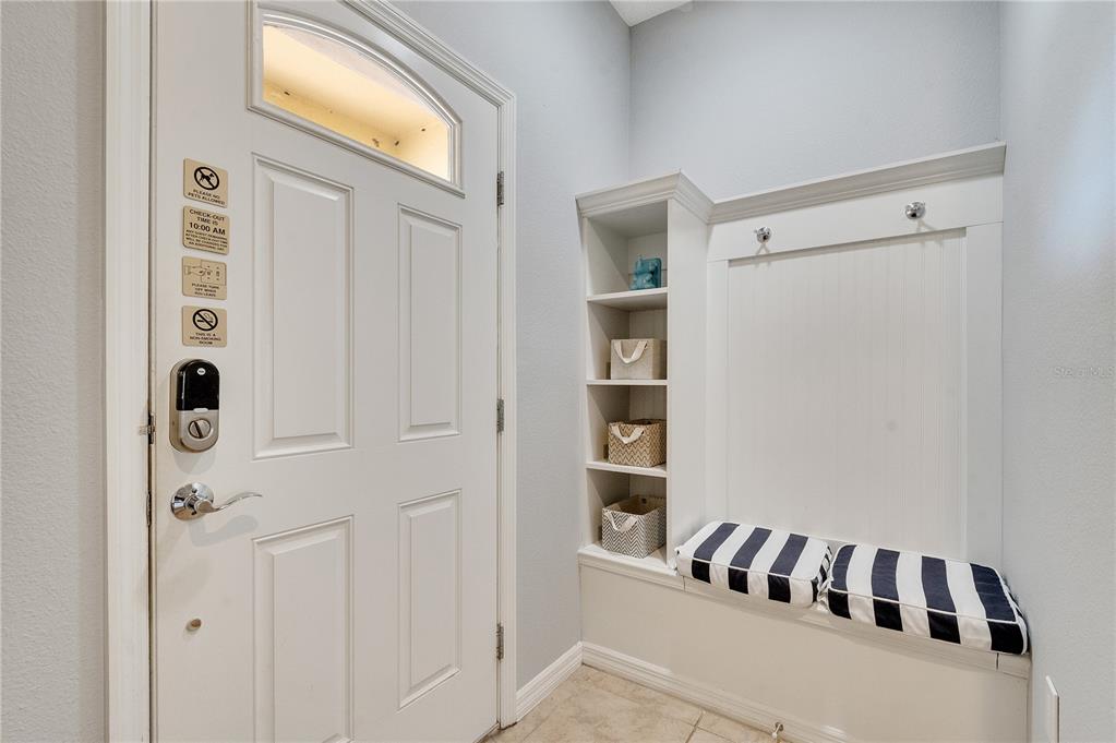 A white entryway features a door with a smart lock and a built-in storage bench — 8827 GENEVE COURT, KISSIMMEE, FL