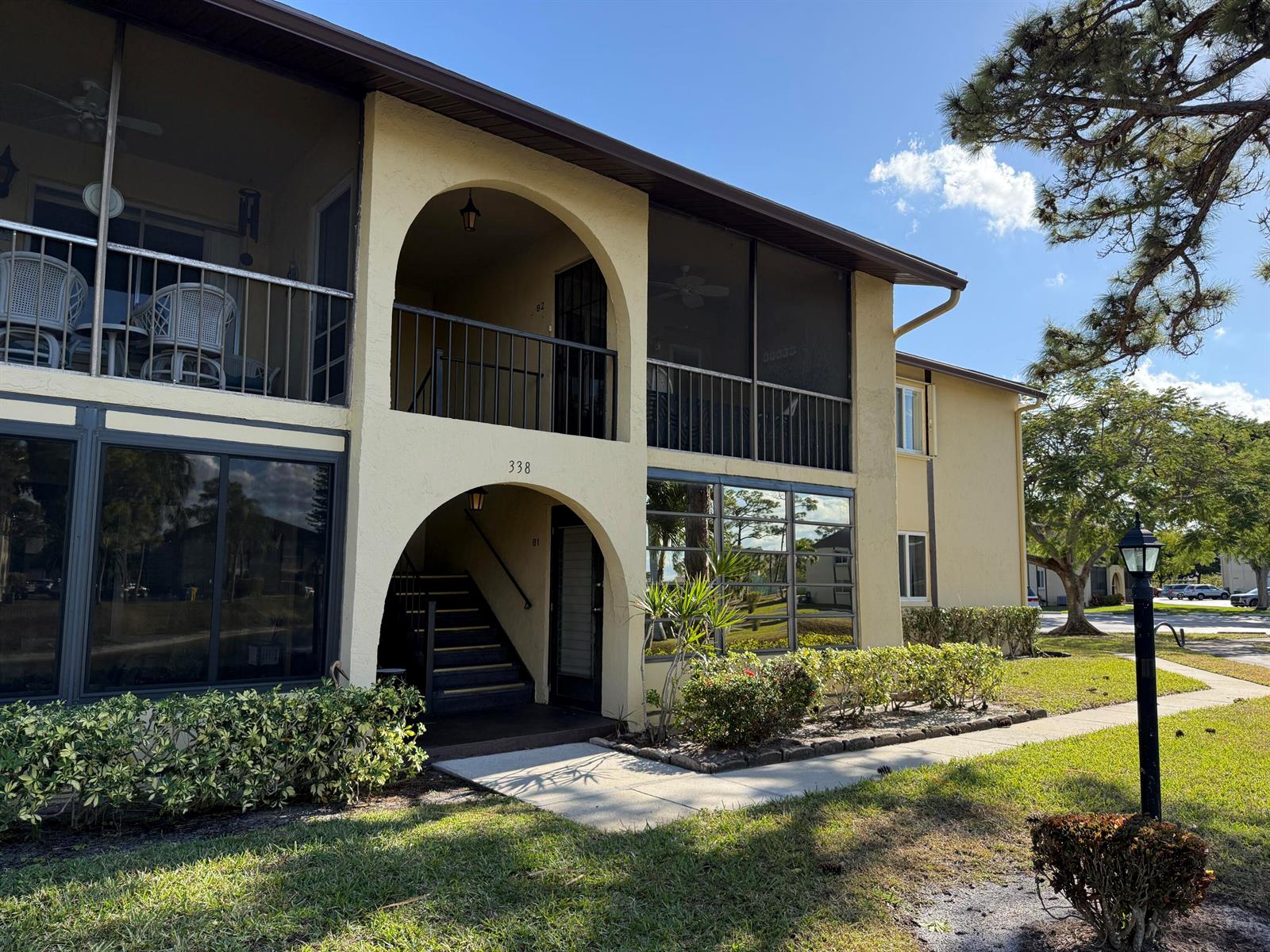 A two-story apartment building features arched entryways, screened balconies, and a landscaped front lawn — 338 Pine Ridge Circle # 2, FL 33463, FL