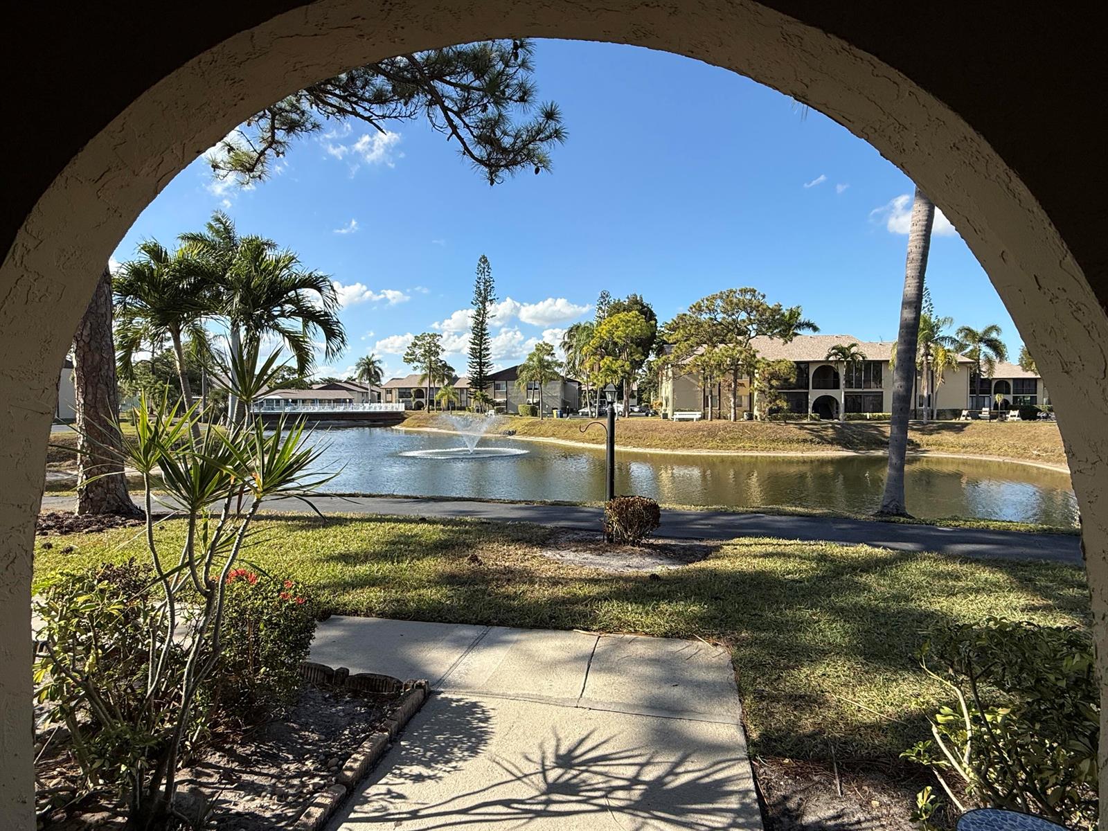 A view of a pond with a fountain framed by an arched entryway — 338 Pine Ridge Circle # 2, FL 33463, FL