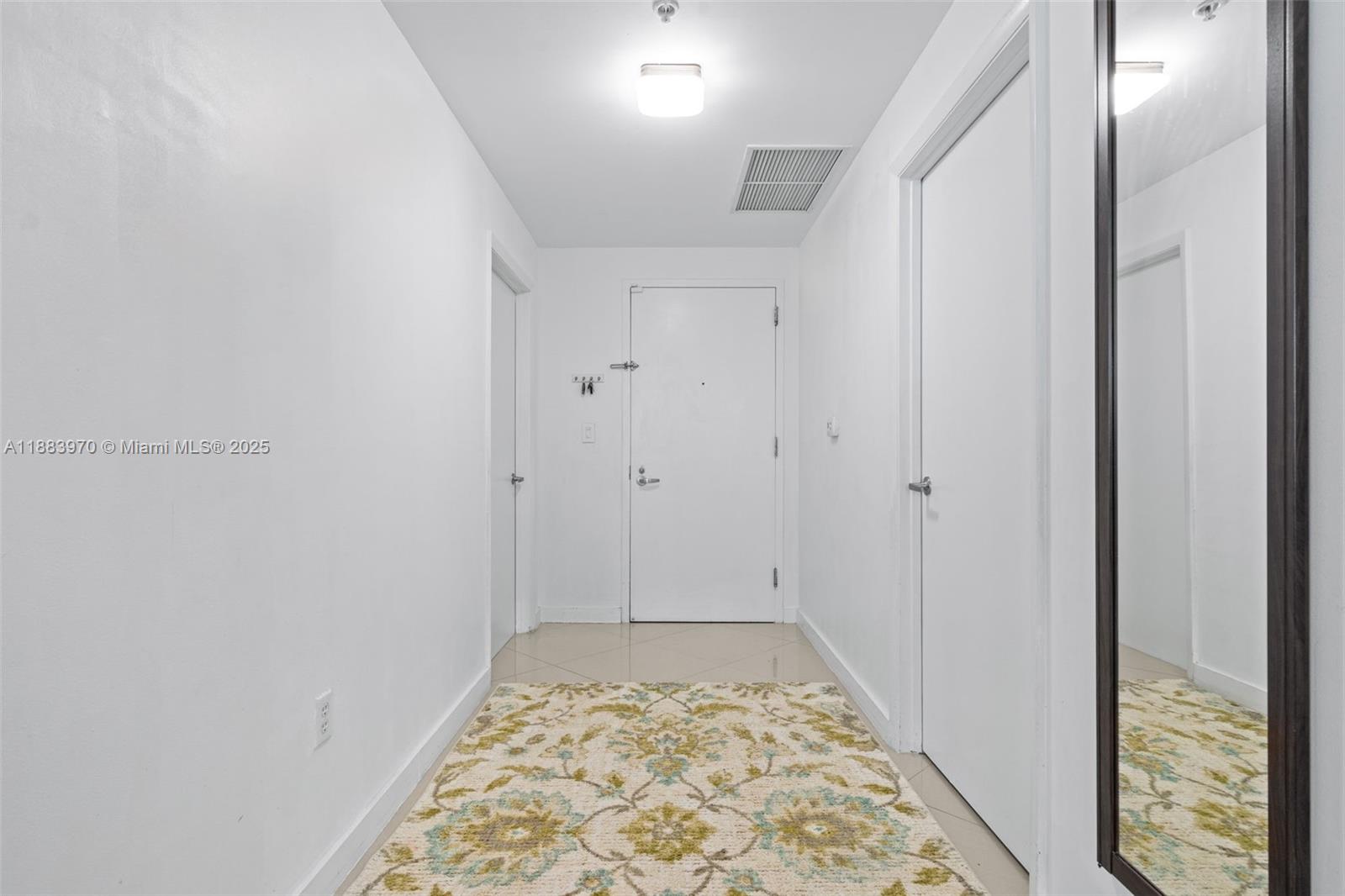 A hallway with white walls, tiled floors, a patterned rug, and three white doors — 1900 N Bayshore Dr # 4018, Miami FL 33132, MIAMI, FL