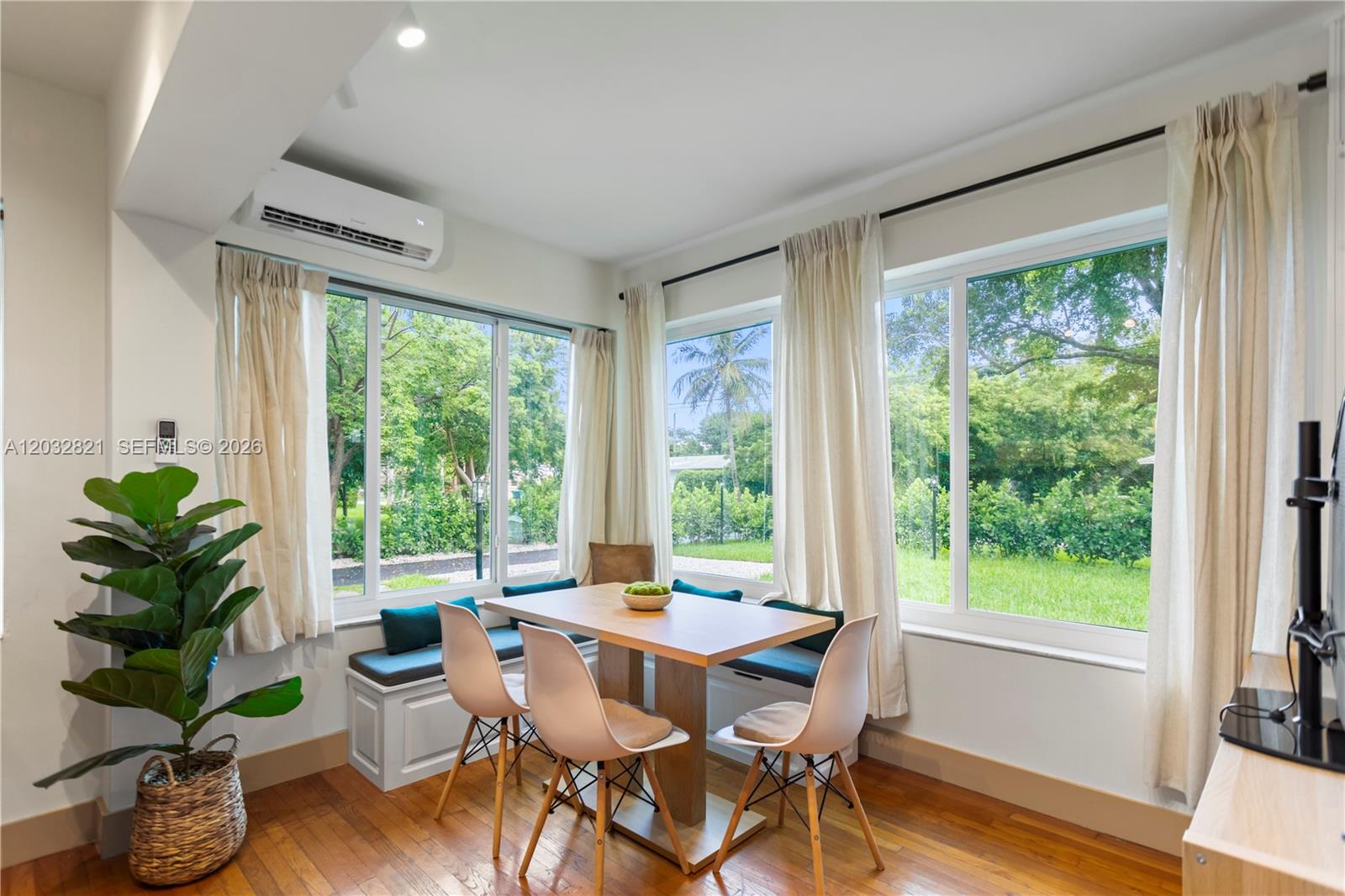 A dining area features a wooden table, chairs, built-in bench seating, and large windows — 499 NE 112th St, Miami FL 33161, MIAMI, FL