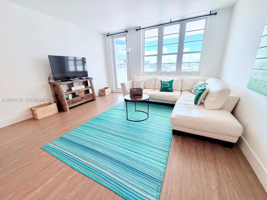 A living room features a white sectional sofa, a blue striped rug, and a television — 100 Lincoln Rd # 922, Miami Beach FL 33139, MIAMI BEACH, FL