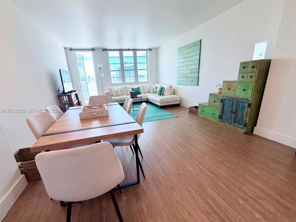 A living and dining area features wood-look flooring, a white sectional sofa, and a wooden table — 100 Lincoln Rd # 922, Miami Beach FL 33139, MIAMI BEACH, FL