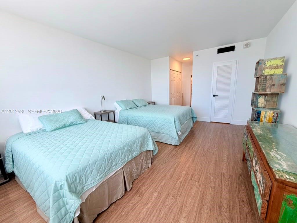 A bedroom features two beds with light blue quilts, wood-look flooring, and a rustic dresser — 100 Lincoln Rd # 922, Miami Beach FL 33139, MIAMI BEACH, FL