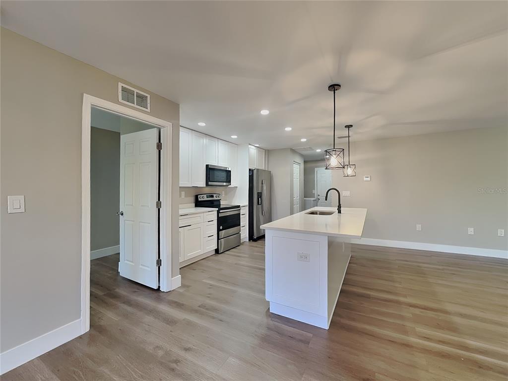 A modern kitchen features white cabinetry, stainless steel appliances, and a central island with seating — 15476 CHAMBERLAIN BOULEVARD, PORT CHARLOTTE, FL