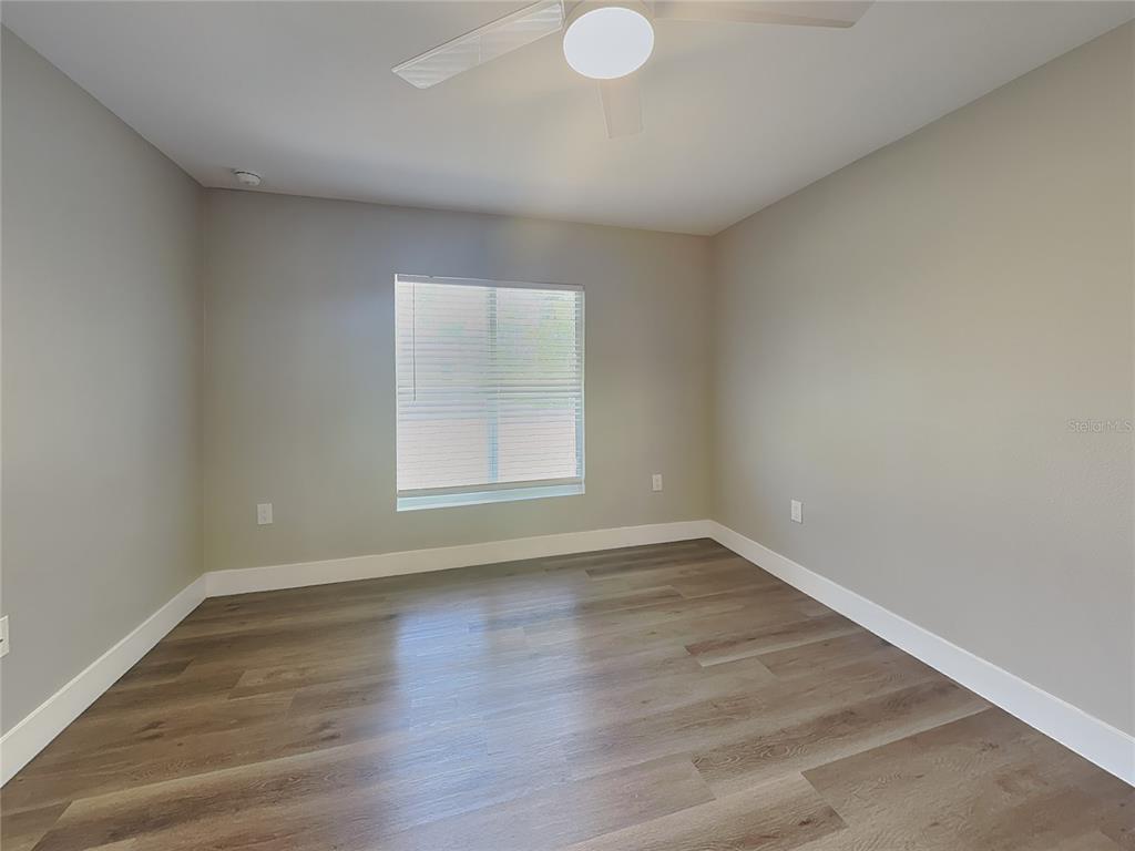 An empty bedroom features light gray walls, white trim, and wood-look flooring — 15476 CHAMBERLAIN BOULEVARD, PORT CHARLOTTE, FL