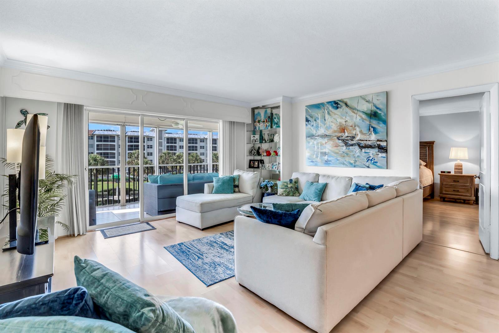A living room features a white sectional sofa, blue accents, and a sliding door to a balcony — 2871 N Ocean Boulevard # C307, Boca Raton FL 33431, BOCA RATON, FL