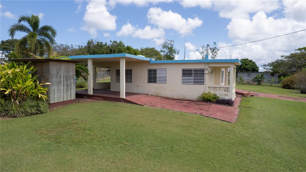A single-story house with a flat roof, a covered porch, and a detached wooden shed — 195 CALLE ALMENDRO, VIEQUES, PR