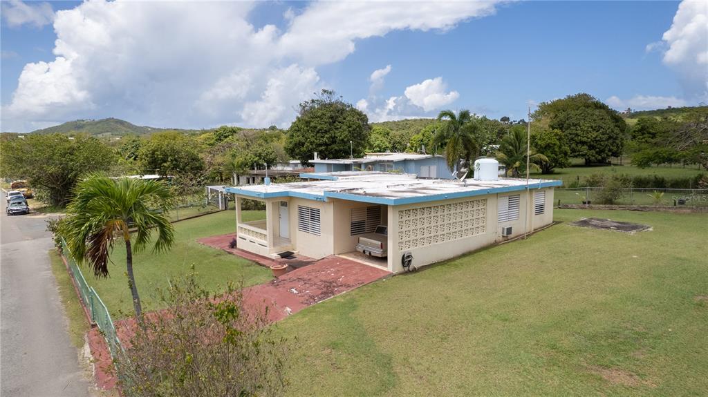 An exterior view of a single-story house with a carport, flat roof, and grassy yard — 195 CALLE ALMENDRO, VIEQUES, PR