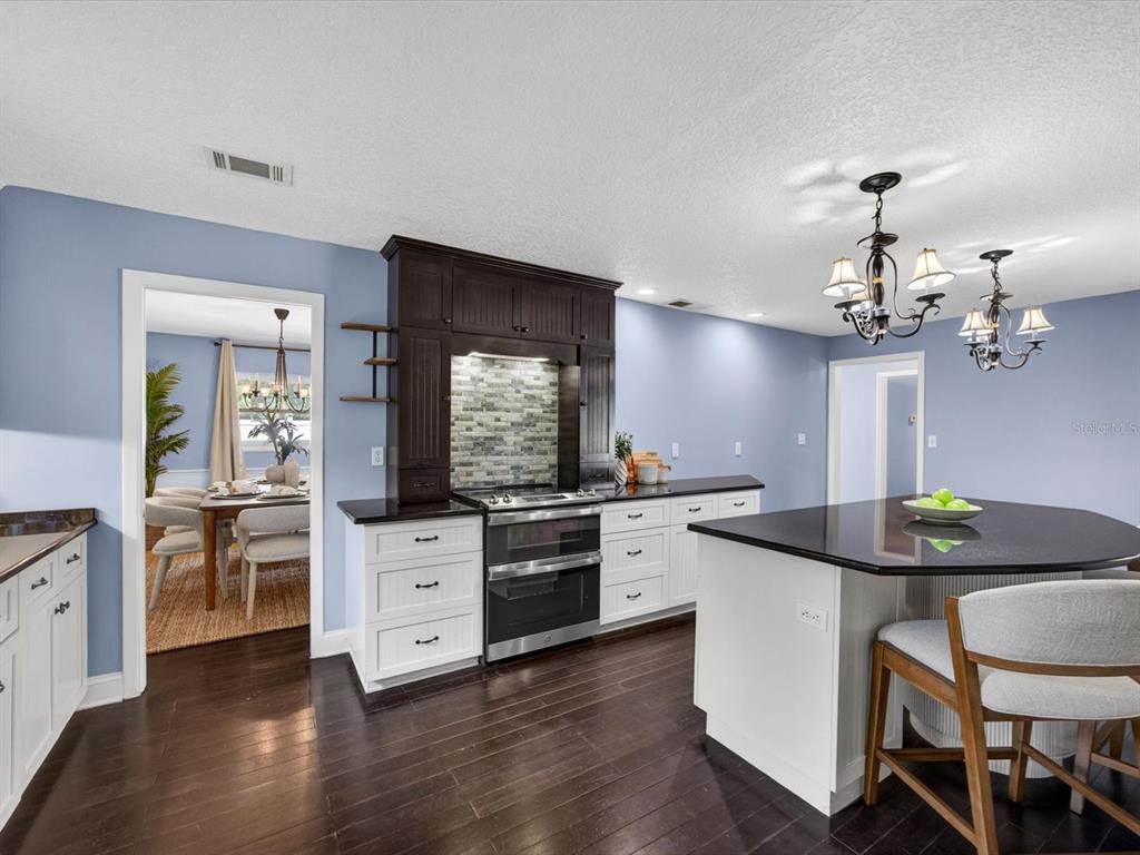 A kitchen with white cabinets, dark countertops, a dark wood range hood, and blue walls — 333 CORNWALL ROAD, WINTER PARK, FL