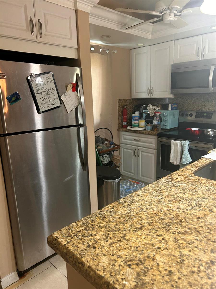 A kitchen features stainless steel appliances, white cabinets, and granite countertops — 2214 NE 1st Way # 106, Boynton Beach FL 33435, BOYNTON BEACH, FL