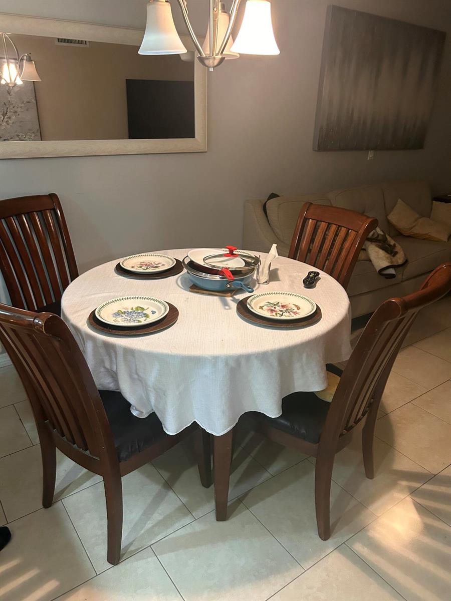 A dining area features a round table with four wooden chairs and a light fixture — 2214 NE 1st Way # 106, Boynton Beach FL 33435, BOYNTON BEACH, FL