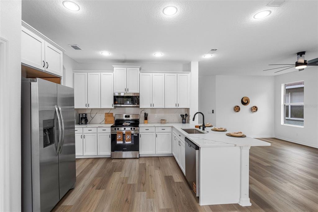 A modern kitchen features white cabinets, stainless steel appliances, and a marble-topped island — 2509 RIVER BRIAR BOULEVARD, RUSKIN, FL