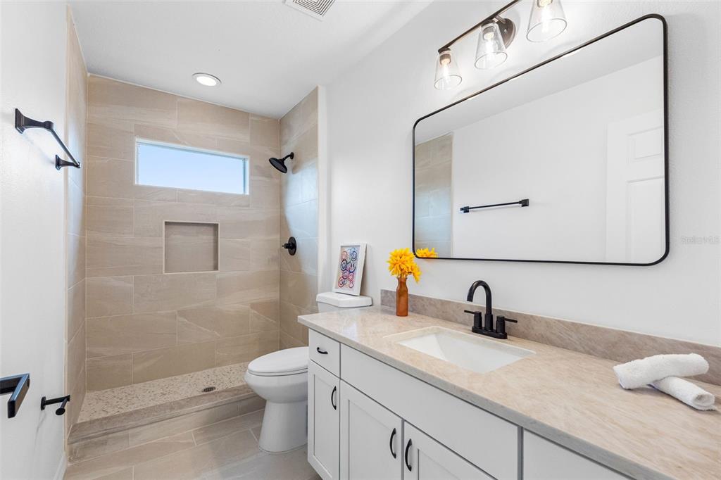 A bathroom features a tiled walk-in shower, a white vanity, and a rectangular wall mirror — 2509 RIVER BRIAR BOULEVARD, RUSKIN, FL