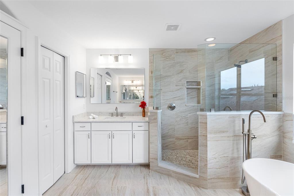 A modern bathroom features a white vanity, a glass-enclosed walk-in shower, and a freestanding tub — 2509 RIVER BRIAR BOULEVARD, RUSKIN, FL