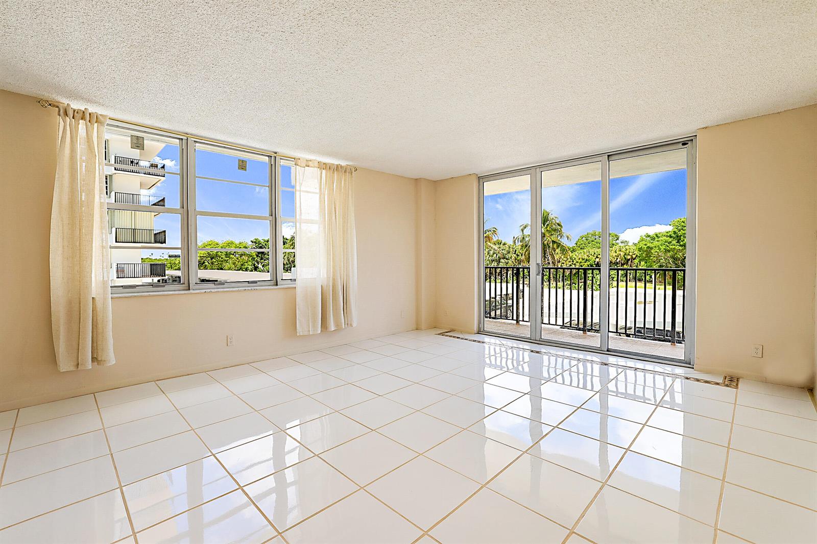 An empty room with white tile floors, beige walls, large windows, and a sliding glass door — 2121 N Ocean Boulevard # 302e, Boca Raton FL 33431, BOCA RATON, FL