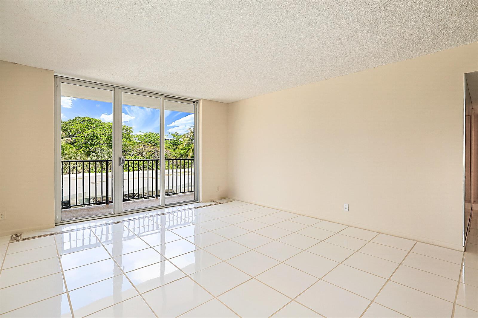 An empty room with white tile flooring, beige walls, and a sliding glass door balcony — 2121 N Ocean Boulevard # 302e, Boca Raton FL 33431, BOCA RATON, FL