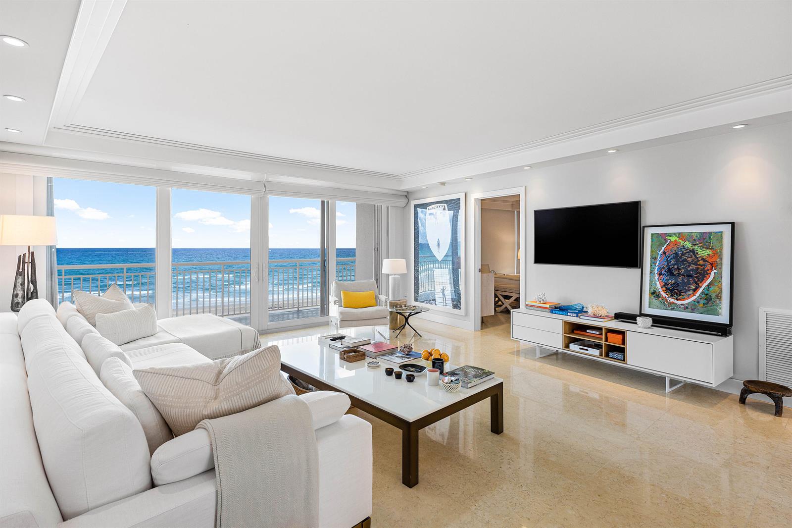 A bright living room features white furniture, a coffee table, and floor-to-ceiling windows overlooking the ocean — 2780 S Ocean Boulevard # 401, Palm Beach FL 33480, PALM BEACH, FL
