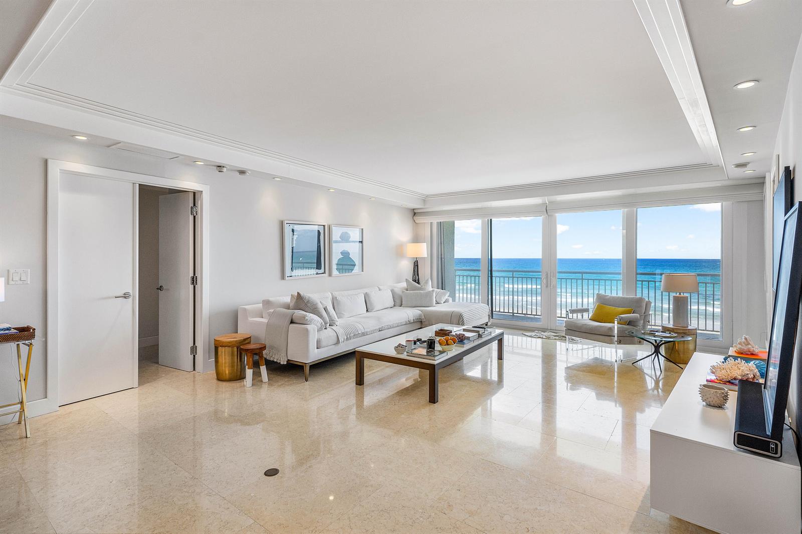 A bright living room features a white sectional sofa, marble floors, and ocean views — 2780 S Ocean Boulevard # 401, Palm Beach FL 33480, PALM BEACH, FL